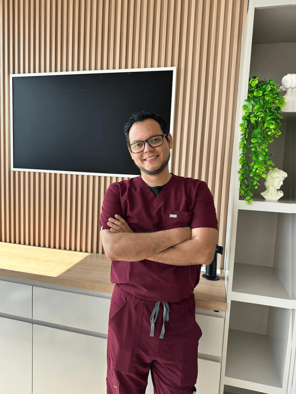 Dr. Cesar Alan Moreno Villegas en su consultorio, con uniforme médico color vino